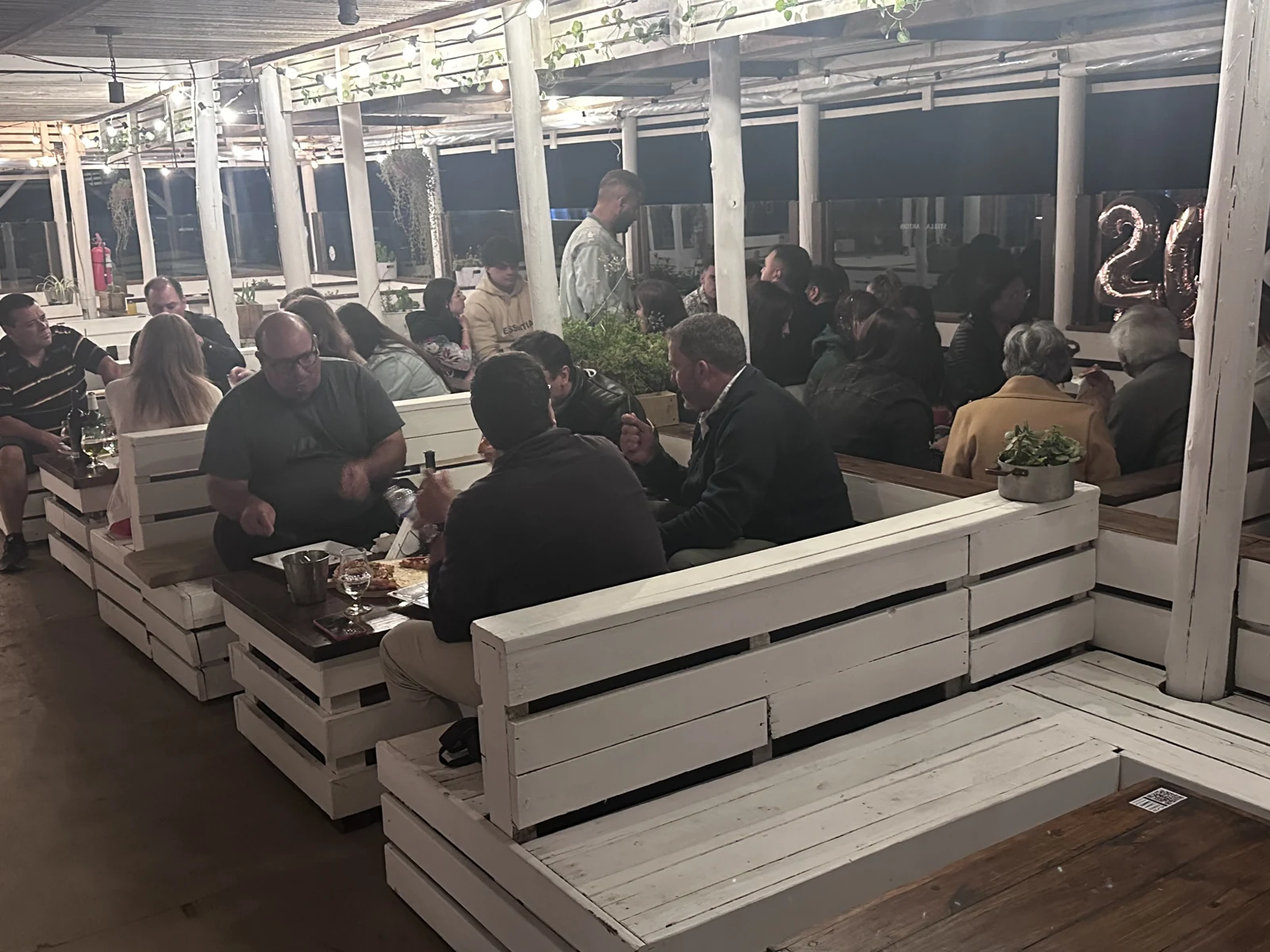 Una cena del archivo SHANTI: mesas compartidas en el deck de noche, bajo guirnaldas de luz.